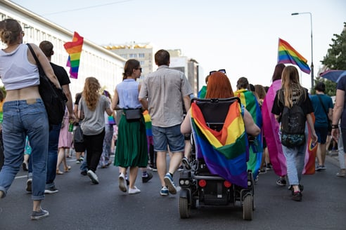 woman with a pride flag on wheelchair at pride parade
