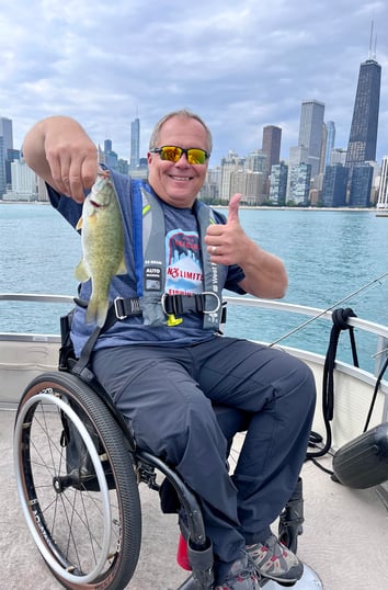 Man in wheelchair with a fish in hand on boat