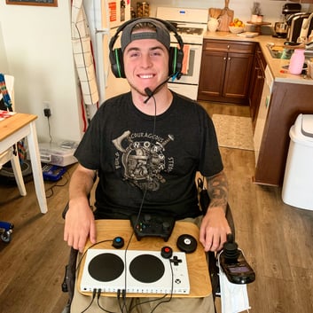 Zack holding his adaptive controller and wearing headphones