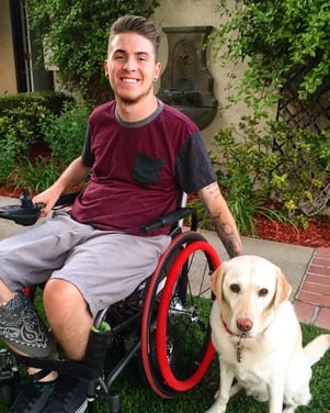 Zack outside in his wheelchair with his dog