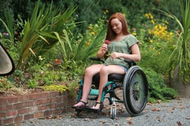 redhaired girl in manual chair holding a flower