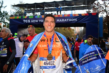 Will wearing an orange Team Reeve shirt with a NYC marathon medal around his neck.