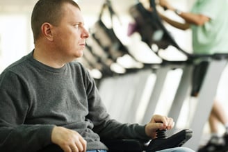 man in gray shirt with treadmills behind him