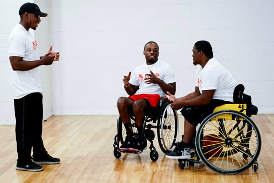 Garrison Redd, a wheelchair user, talking with two other people, one in a wheelchair