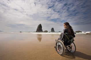 woman un manual wheelchair on a sandy beach