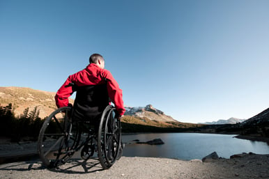 man in wheelchair in front of lake