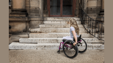 woman in wheelchair in front of stairs