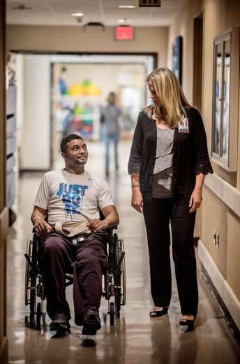 person in wheelchair in hallway talking to doctor/coach