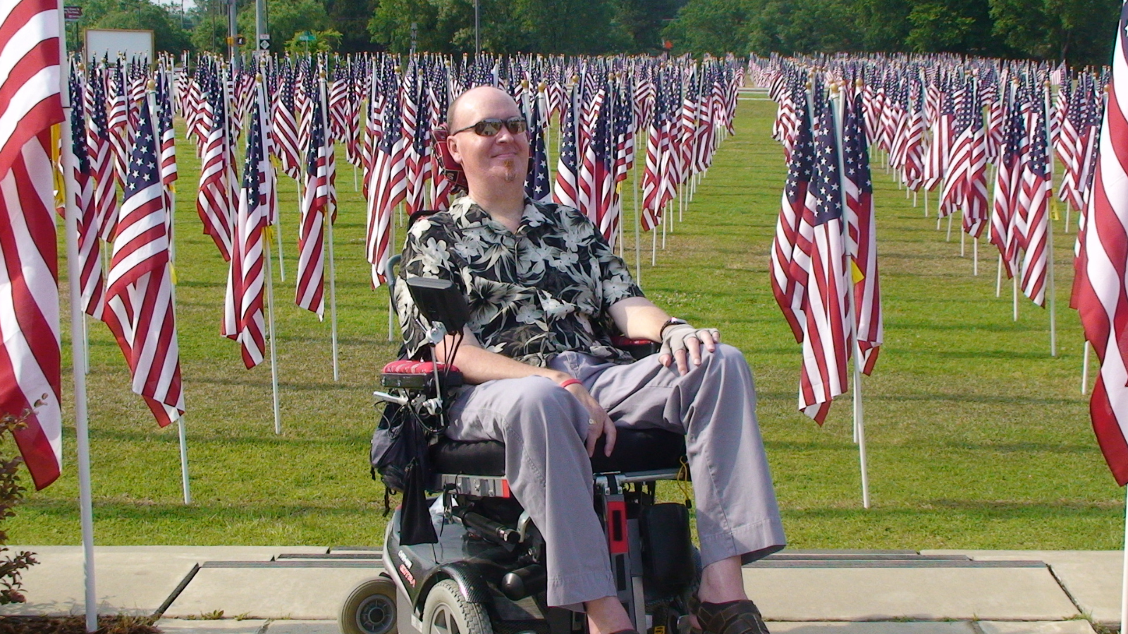 male in wheelchair sitting infront of american flags