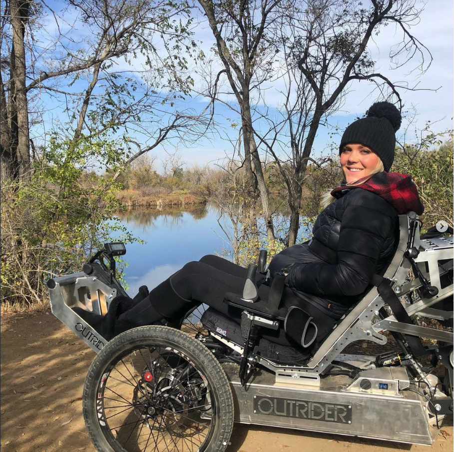 Ellie using an Outrider chair in front of a lake