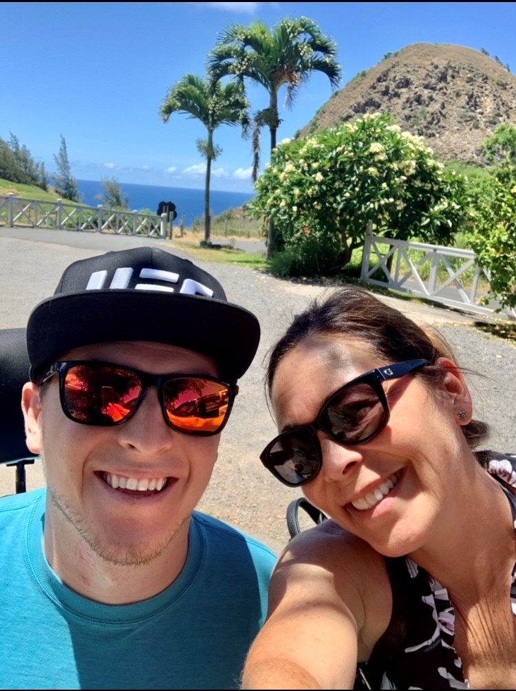 Selfie of Amber and Zack with palm trees behind them.