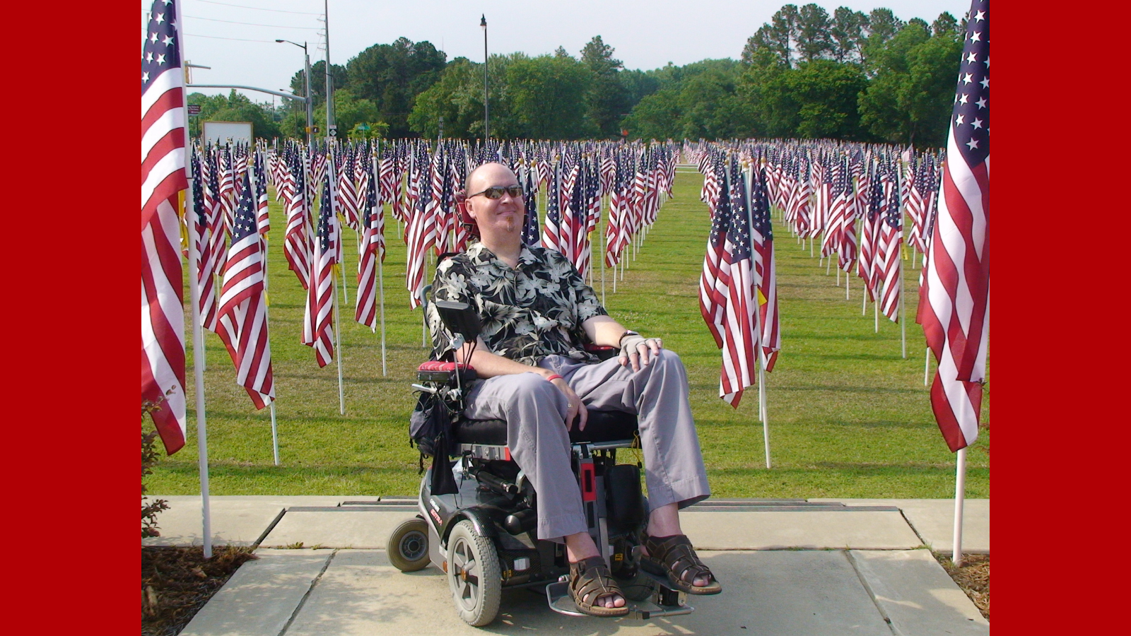man in wheelchair infront of american flags