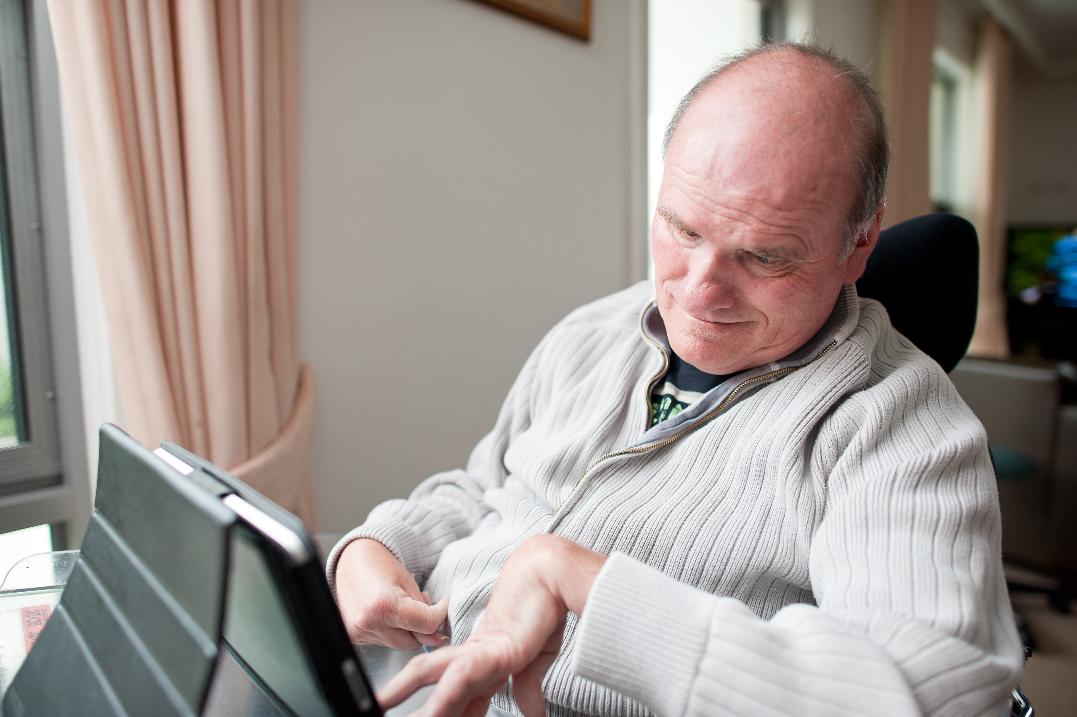 Fifty-five year old man with a disability using computer inside his home.