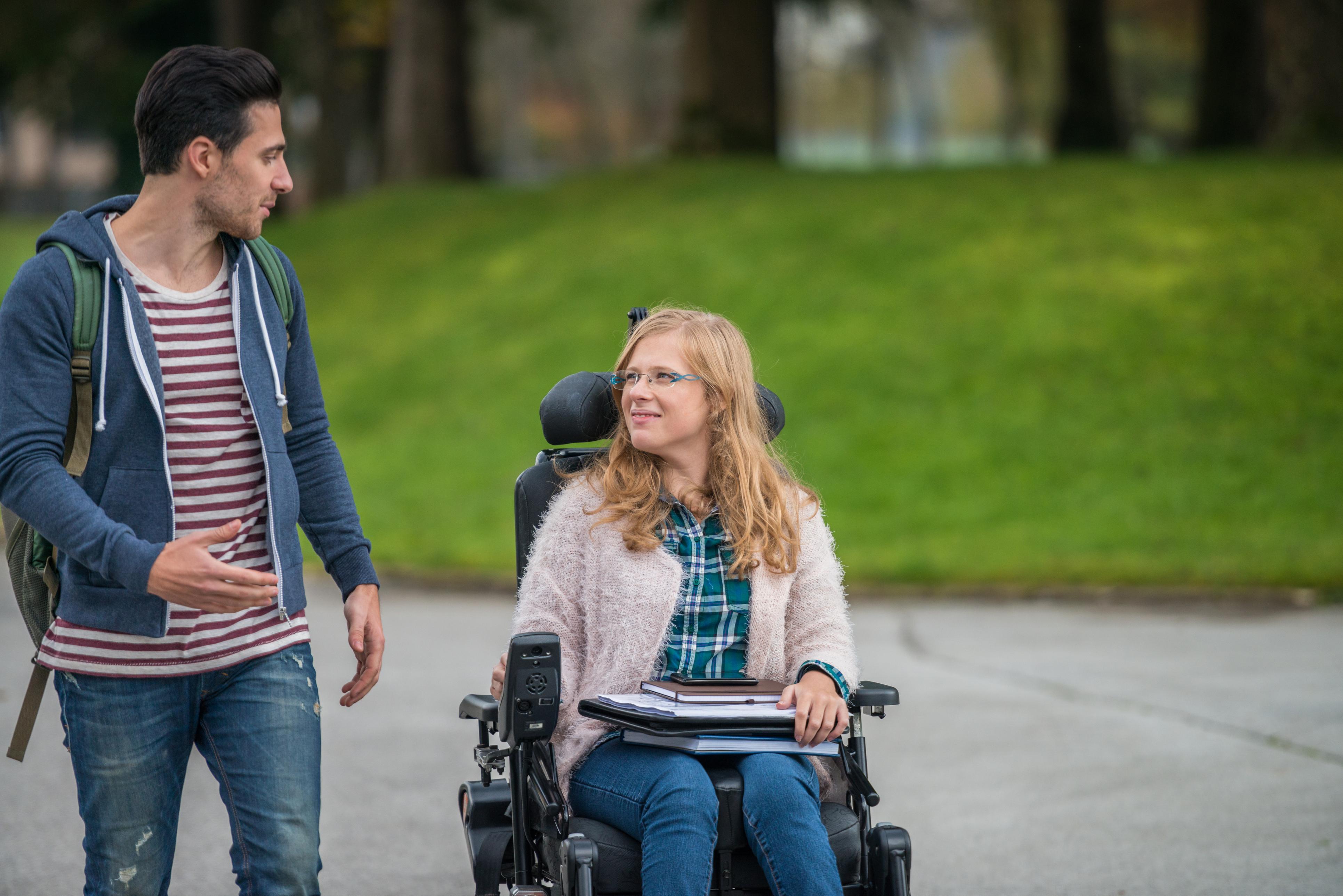 male walking alongside woman in wheelchair